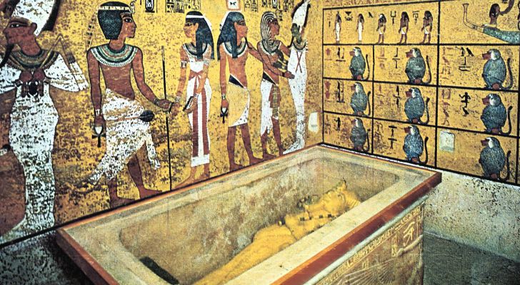 An Egyptian tomb with heiryglyphs on the walls and a mummy