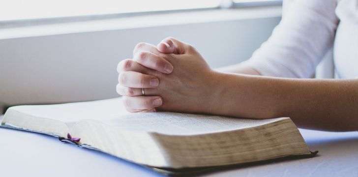 Praying hands on a book.