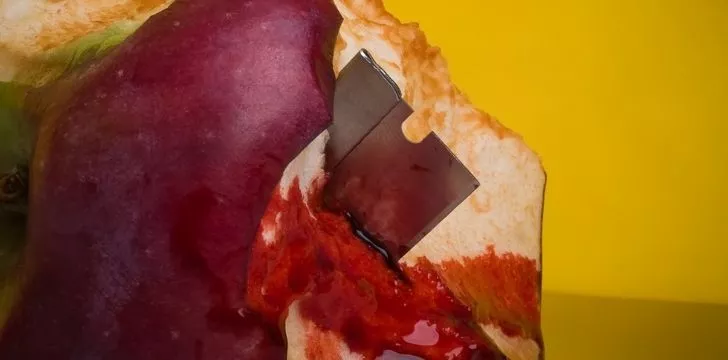 A sharp razor blade inside a half eaten apple dripping in blood