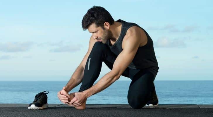 A man tending to a foot injury while out running