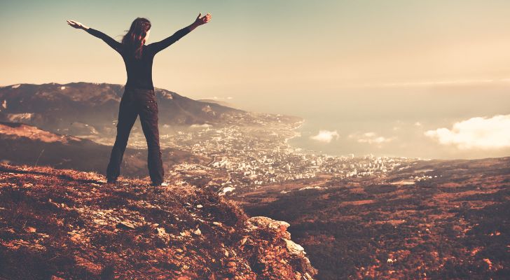 A woman on top of a mountain with her arms up in the air