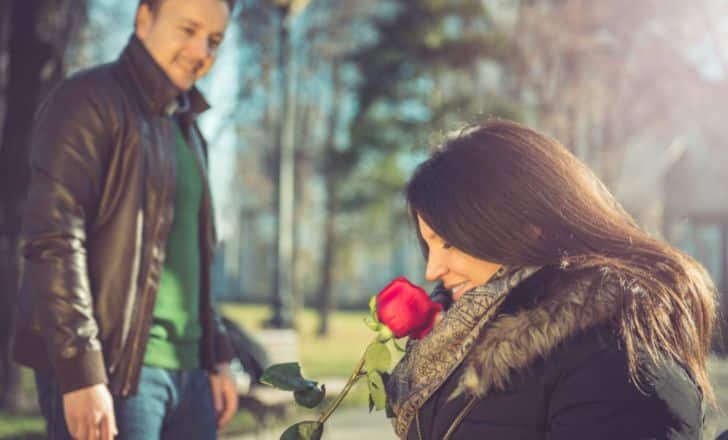 A person smelling a red rose.