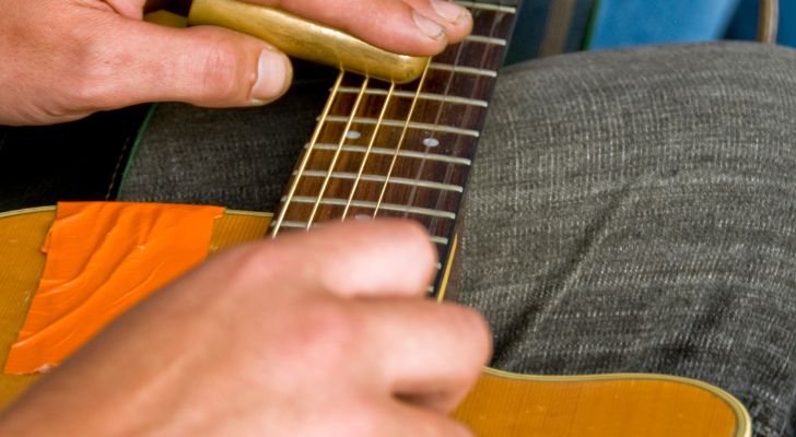 A guitar rests on someone's lap as they play it