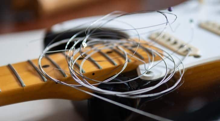 Some guitar strings rest on top of an unstrung guitar