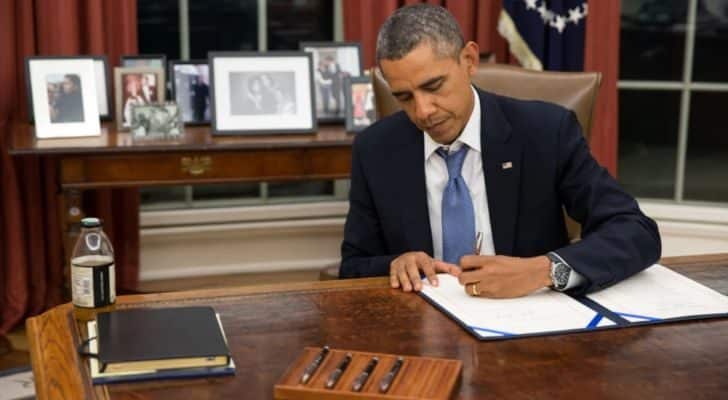 Barack Obama signing a document in the Oval Office