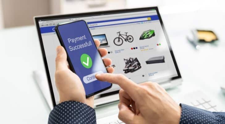 A laptop shows online products available for purchase while a person holds a phone displaying "Payment successful"