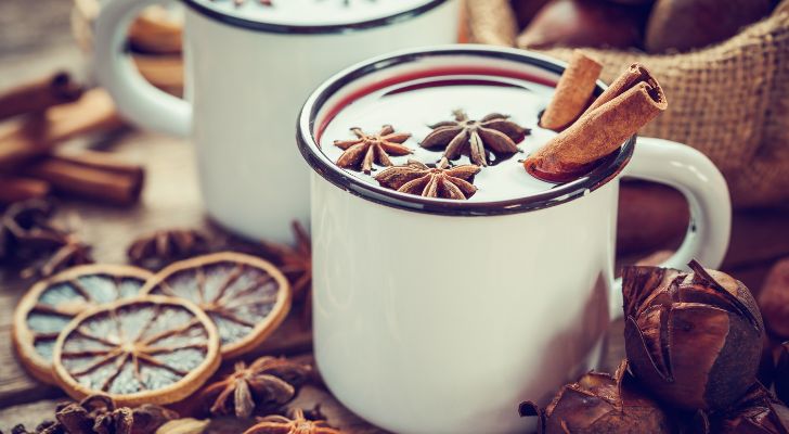 Two ceramic mugs of mulled wine appearing almost white due to the light's reflection