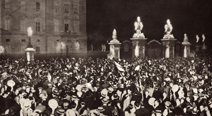 A huge crowd gathers outside a palace as the Royal family address them from a balcony