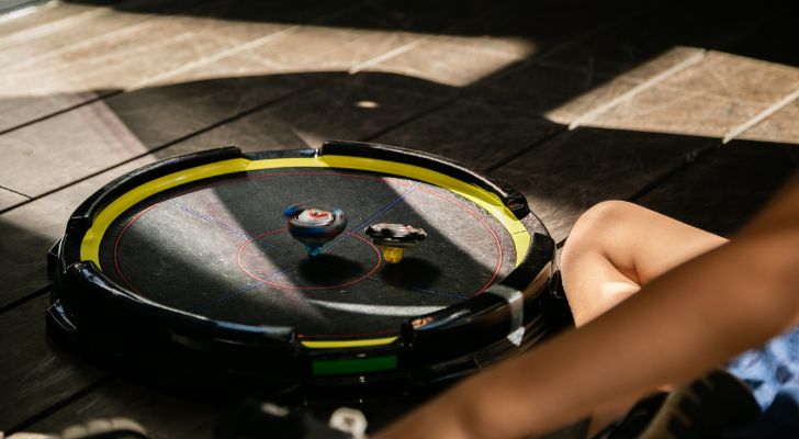 Two Beyblades spin in an arena