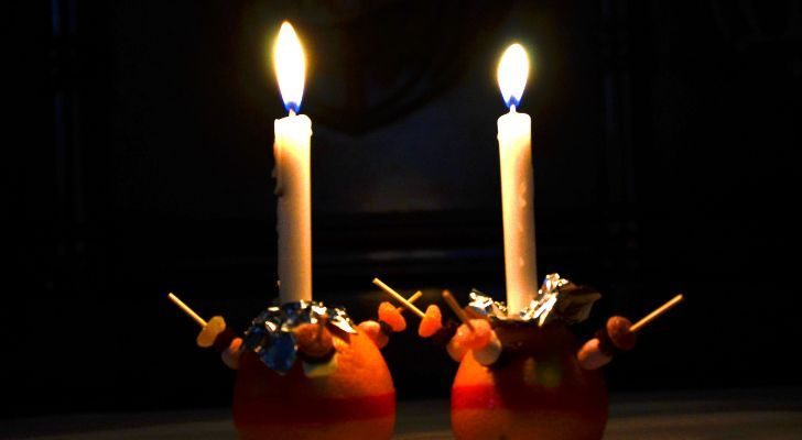 Two lit Christingles placed next to each other in the dark