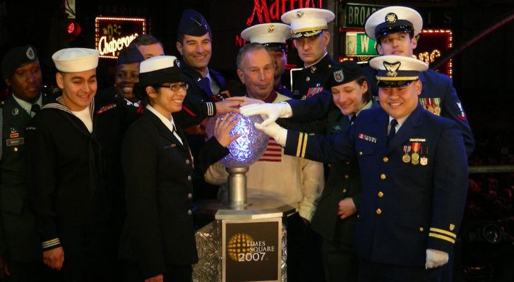 Several members of the Navy lean in to all press the ball drop button together