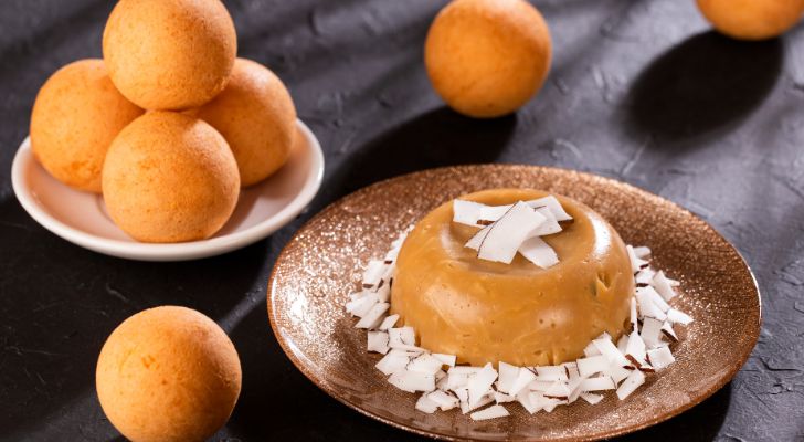 A custard-like desert on a plate, topped with coconut shavvings