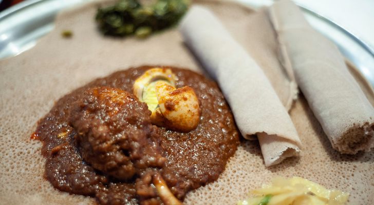 A stewy mixture is served alongside vegetables and flatbread