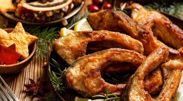 Slices of fried fish with lemon are served alongside other Christmas fare