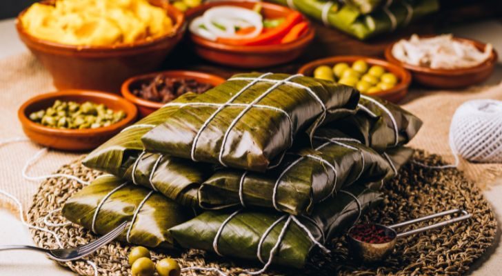 Venezuelan hallacas packages on a table surround by their ingredients