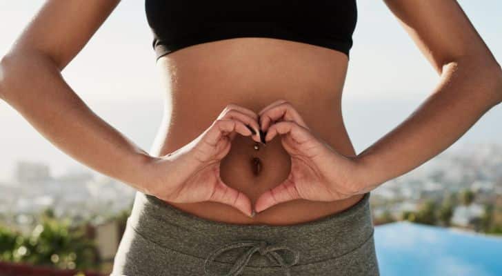 A woman making a heart shape with her hands in front of her belly