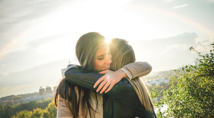 Two female friends hugging in the sunlight