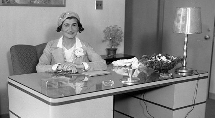 Coco Chanel sitting behind a desk