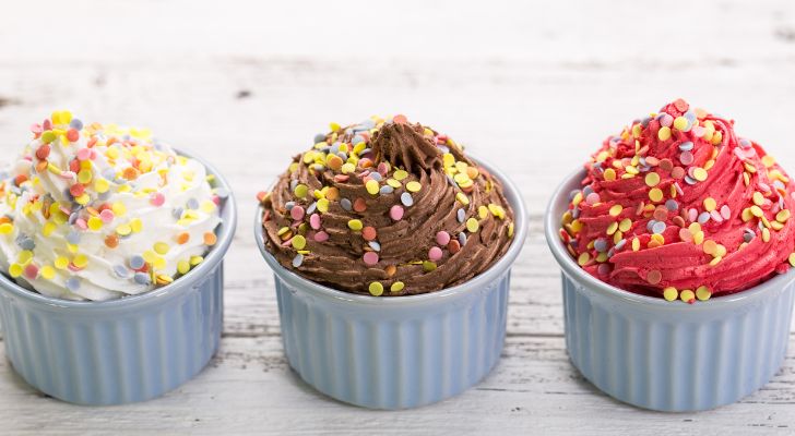 3 different colored frozen yogurts in cups with toppings