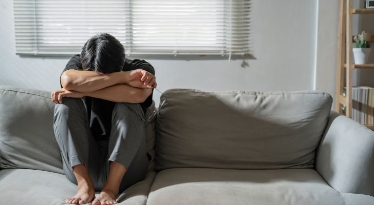 A person on a couch burying their head in their arms