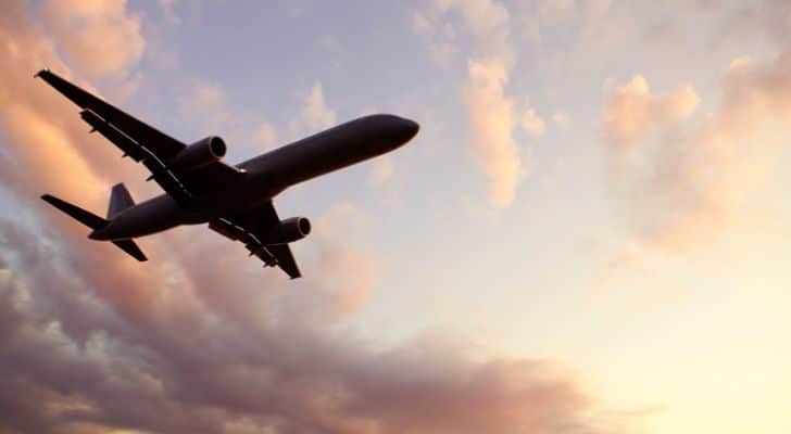 An airplane flying overhead with a sunset in the background