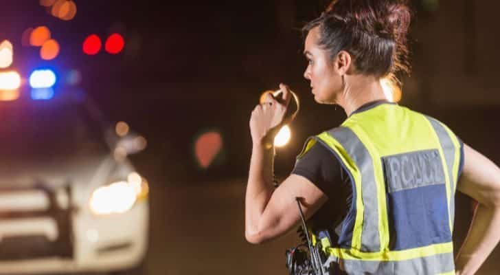 A female police officer using a radio at night