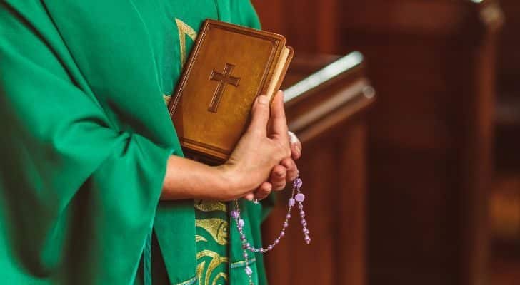 A Catholic priest holding a bible in a church