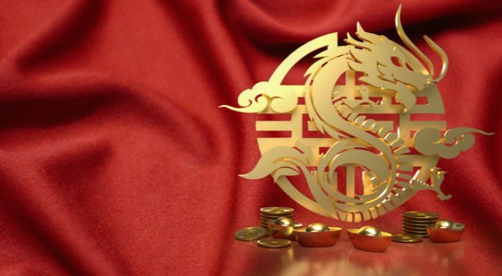 A golden Chinese dragon zodiac symbol on a red satin background.