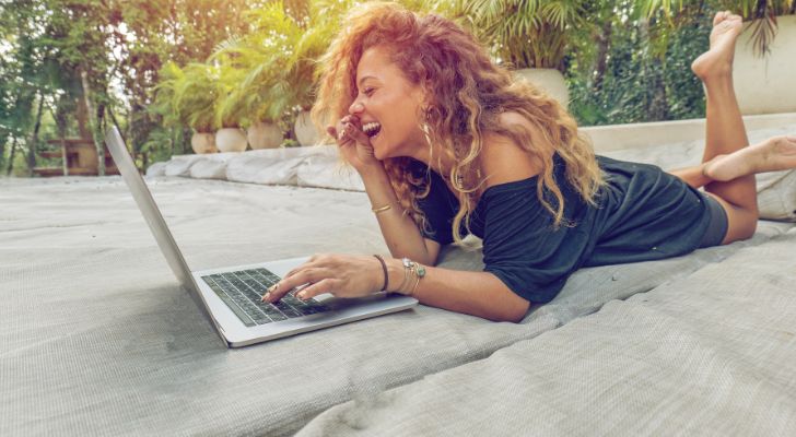 A woman lying on a outdoor bed using a laptop