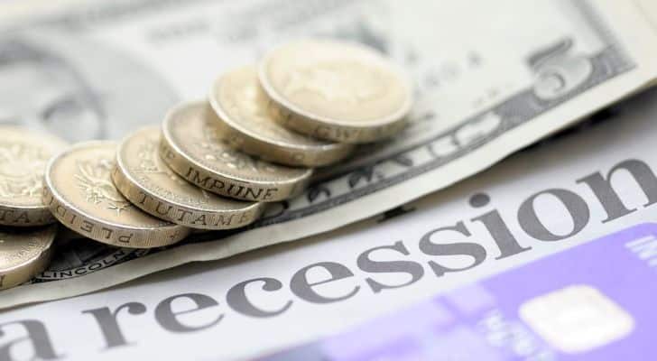 A collection of British pound coins resting on a newspaper with the headline "Recession"