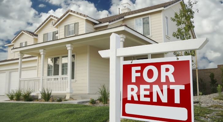 A large white house with a "For Rent" sign in front of it