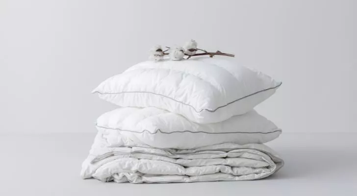 A pile of white cotton pillows with a cotton plant placed on top
