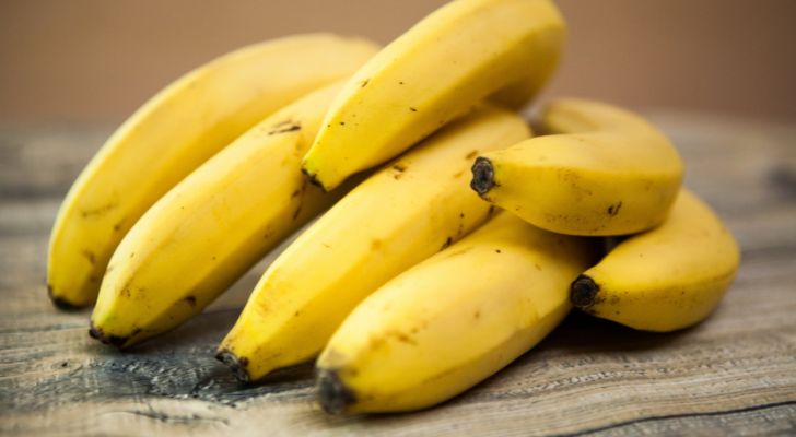 A hand of bananas lying on a wooden table