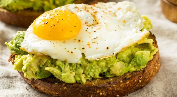 Mashed avocado spread on toast with a fried egg placed on top