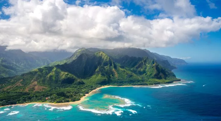 Kauai island, a Hawaiian island covered in mountains and forest next to a pale blue sea