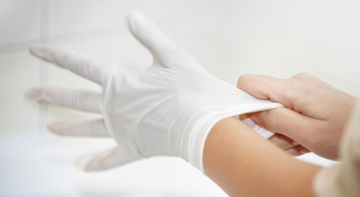 A person pulling a white latex glove onto their hand