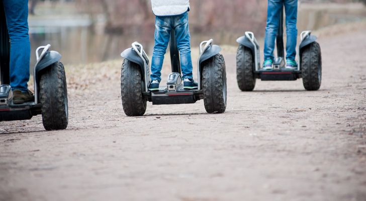 Three people riding segways outside in a line