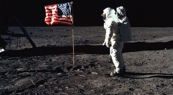 Niel Armstrong standing on the moon next to the American flag