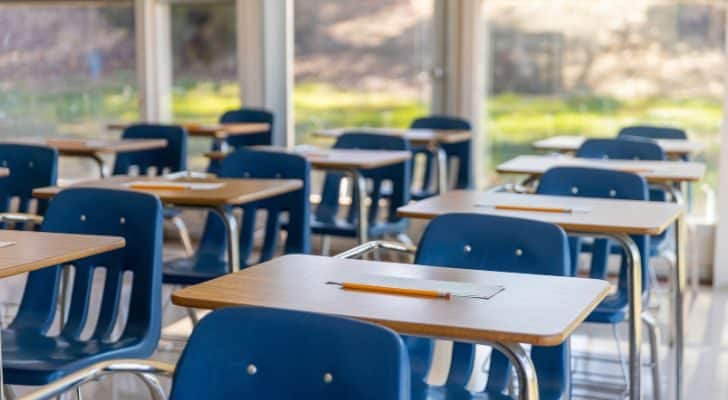 A school's class room full of desks with pencils and paper ready for use