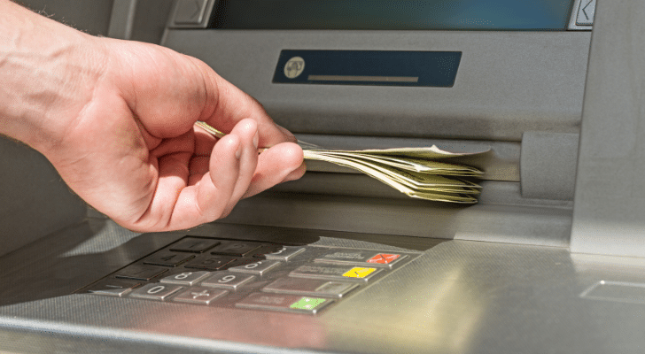 A person's hand taking money out of an ATM