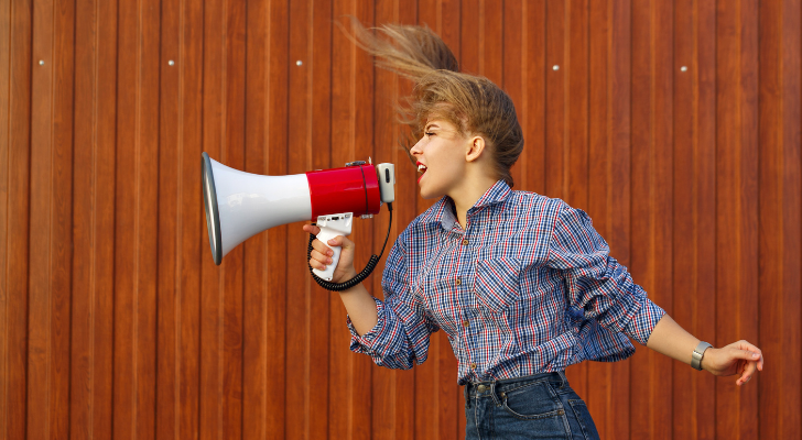 A young woman with a megaphone shouting in the wind