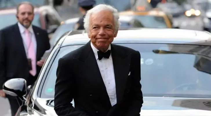 Ralph Lauren wearing a tuxedo and standing in front of a car