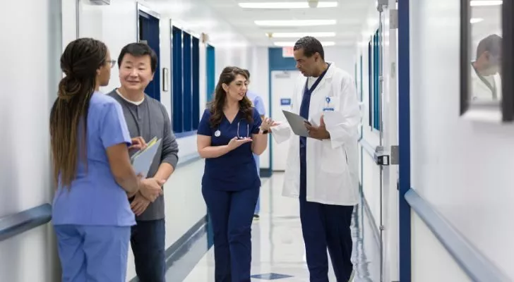 Several doctors discussing things in a hospital hallway