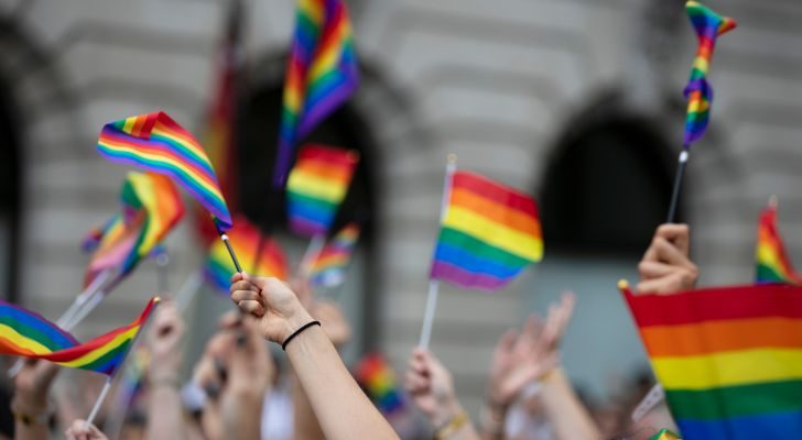 A crowd of people waving miniature pride flags overhead