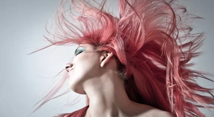 A woman with dyed pink hair whips her head around, flicking her hair