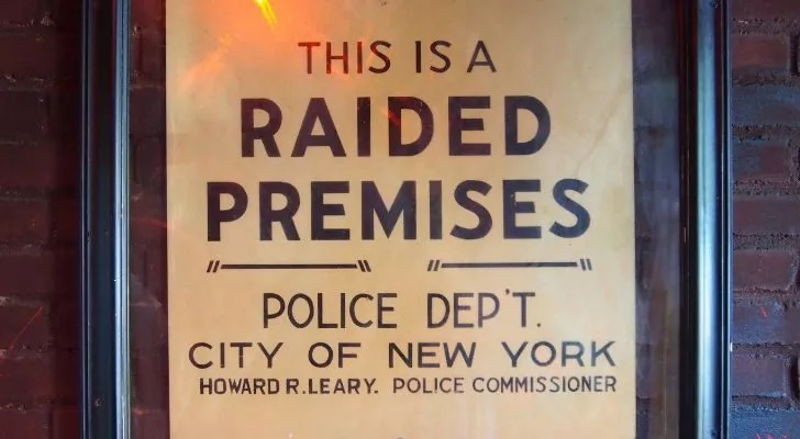 A sign left by the police reading "Raided Premises" which is now hung inside Stonewall Inn