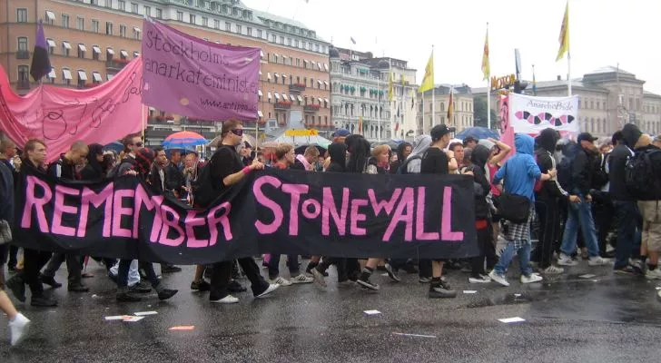 LGBTQIA+ members marching at Stockholm pride with a banner that reads "Remember Stonewall"