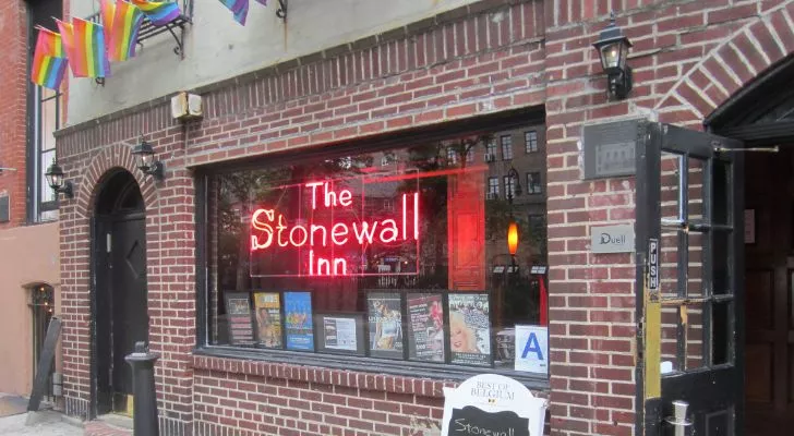 The outside of the modern Stonewall Inn with a large red, neon sign reading "The Stonewall Inn"