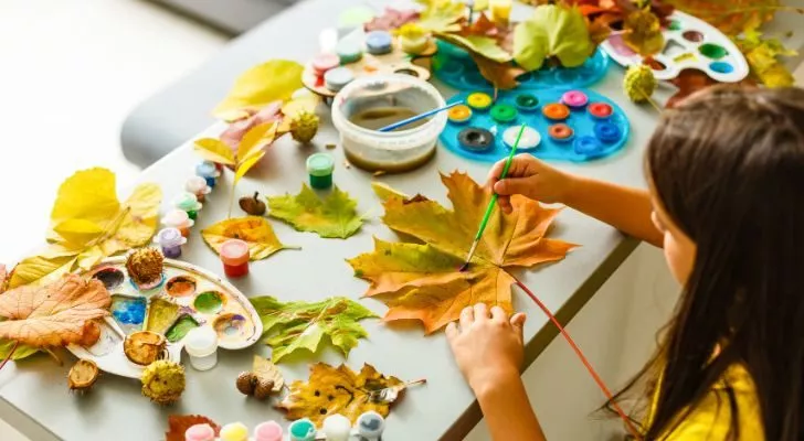 A child making an art project out of leaves and paint