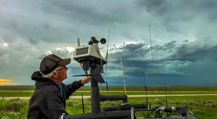 A man with weather tracking equipment looks on at a building storm